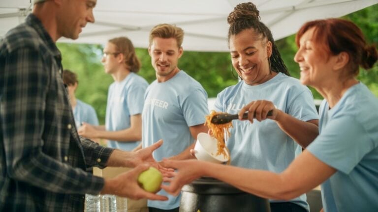 Volunteers giving food to homeless person