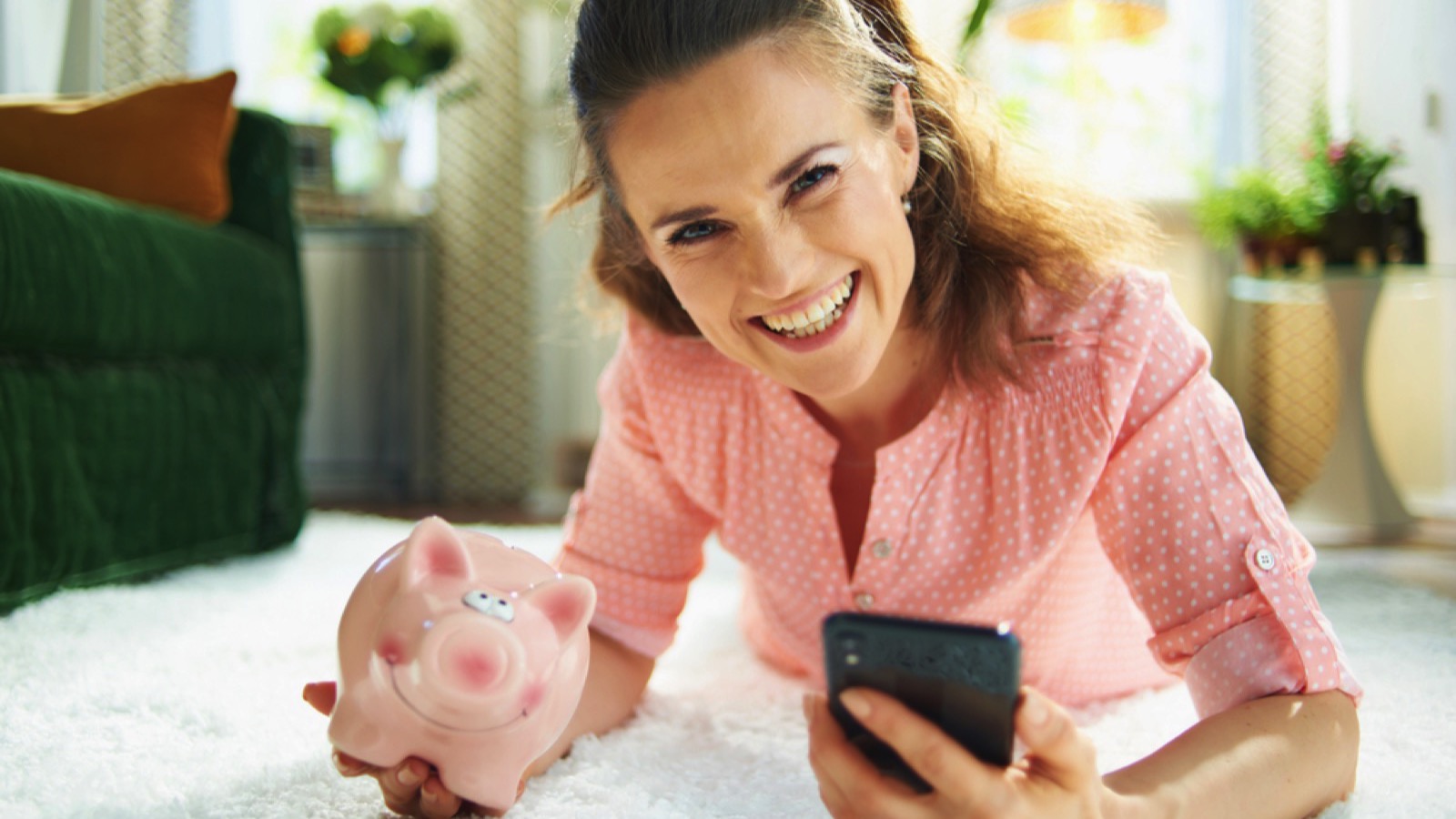 Happy woman with money saving piggy bank