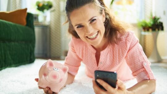 Happy woman with money saving piggy bank