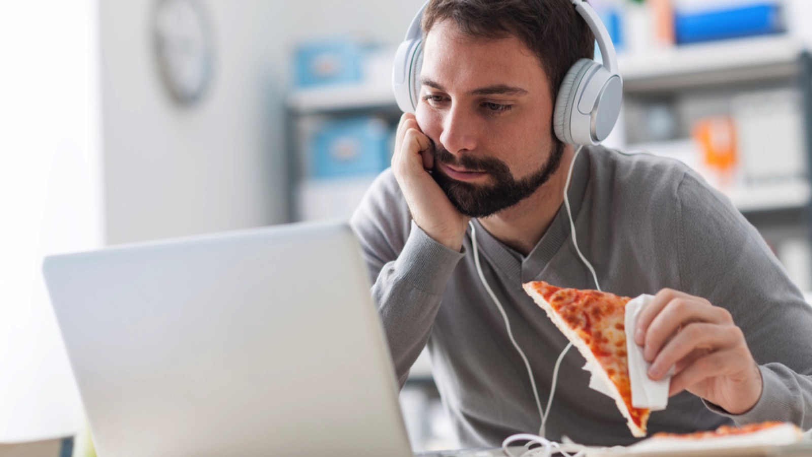 Lazy man siting at desk eating sandwich