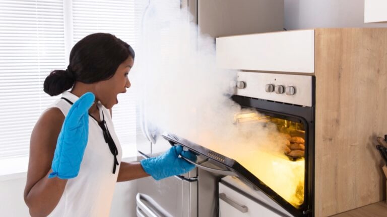 Shocked woman looking at cookies with hot air coming out of oven