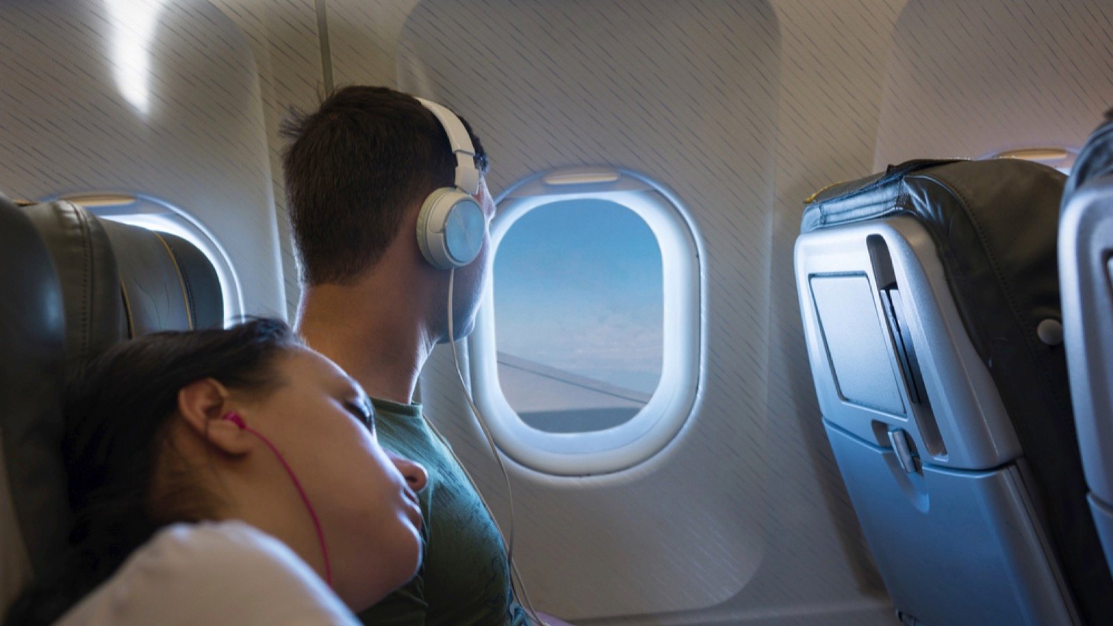 Woman lying on male shoulder in plane