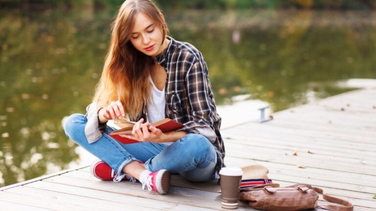 Woman on riverside reading book