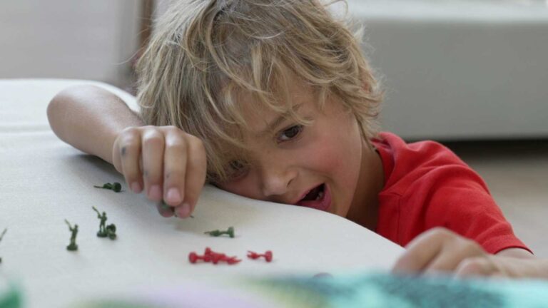 boy playing with miniature combat figurines