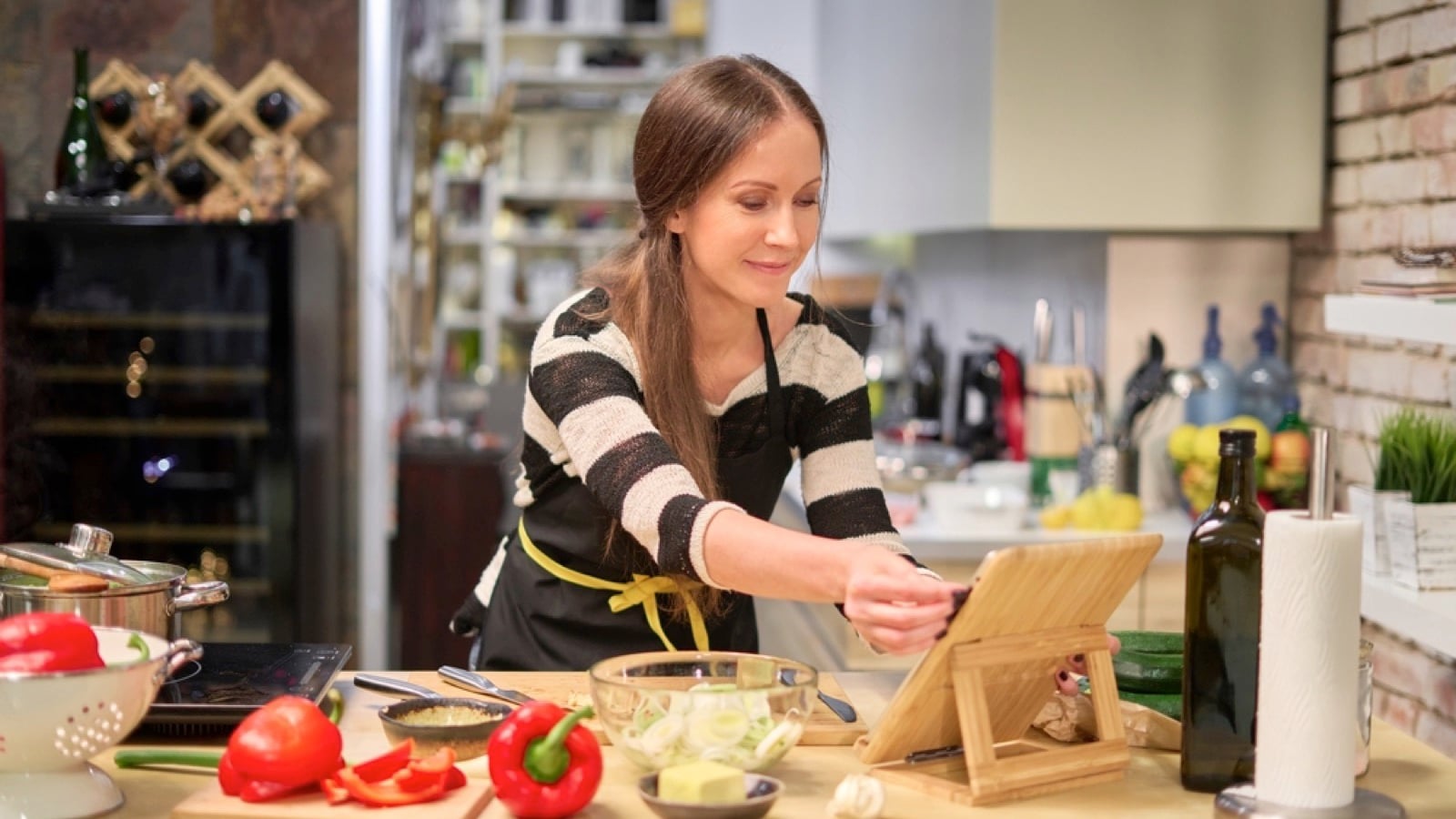 Happy young woman following recipe in tab