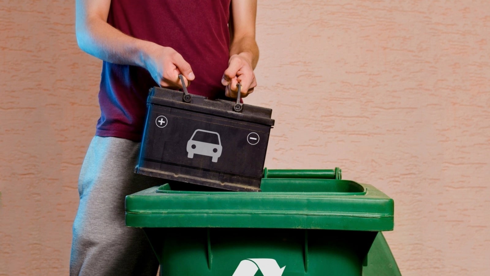 Man throwing old car battery in reusable bin