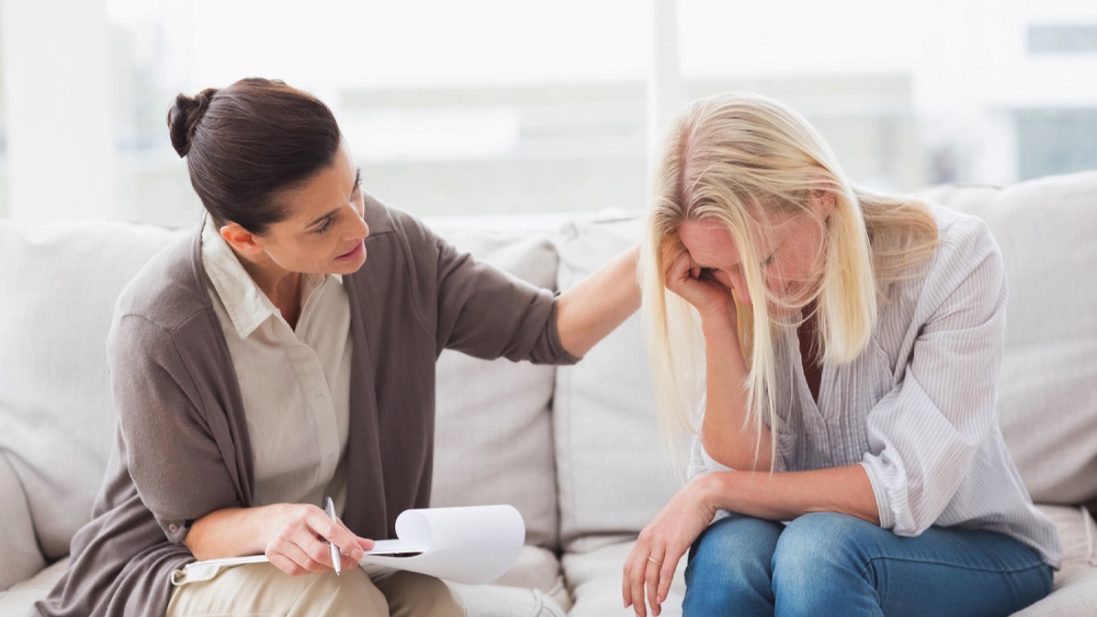 Therapist comforting stressed young woman