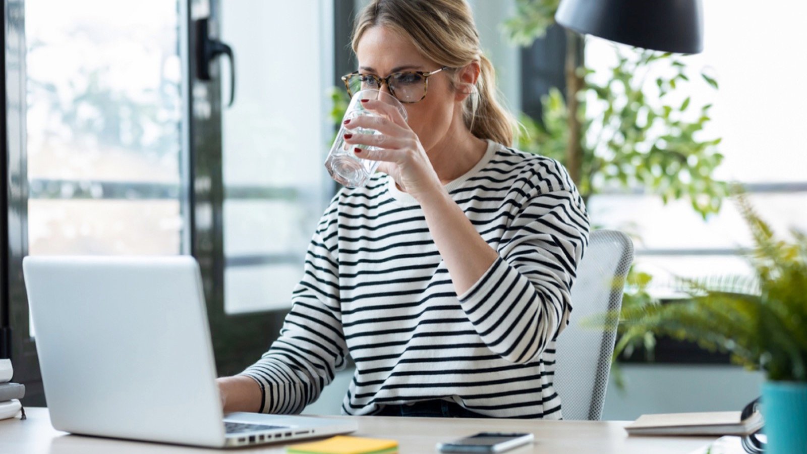 Woman drinking water while working
