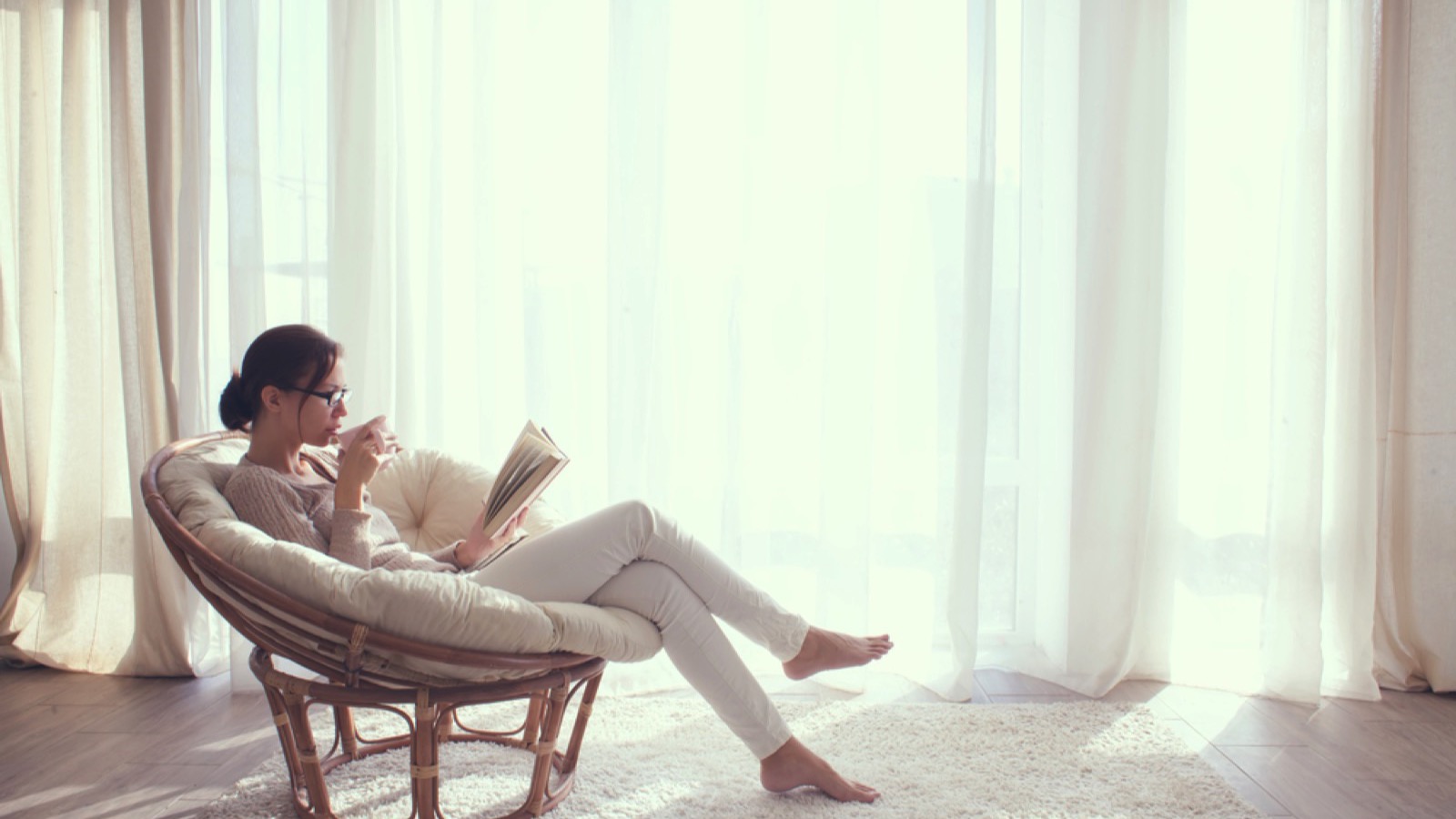 Woman in chair reading book having coffee