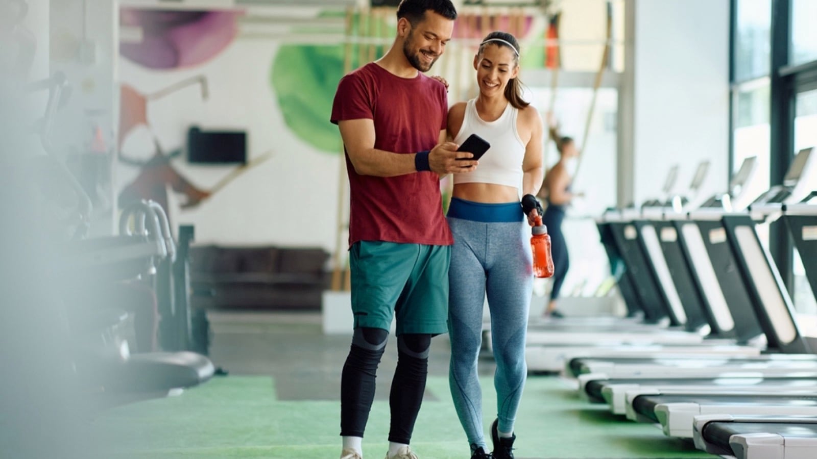 Happy couple using mobile in gym