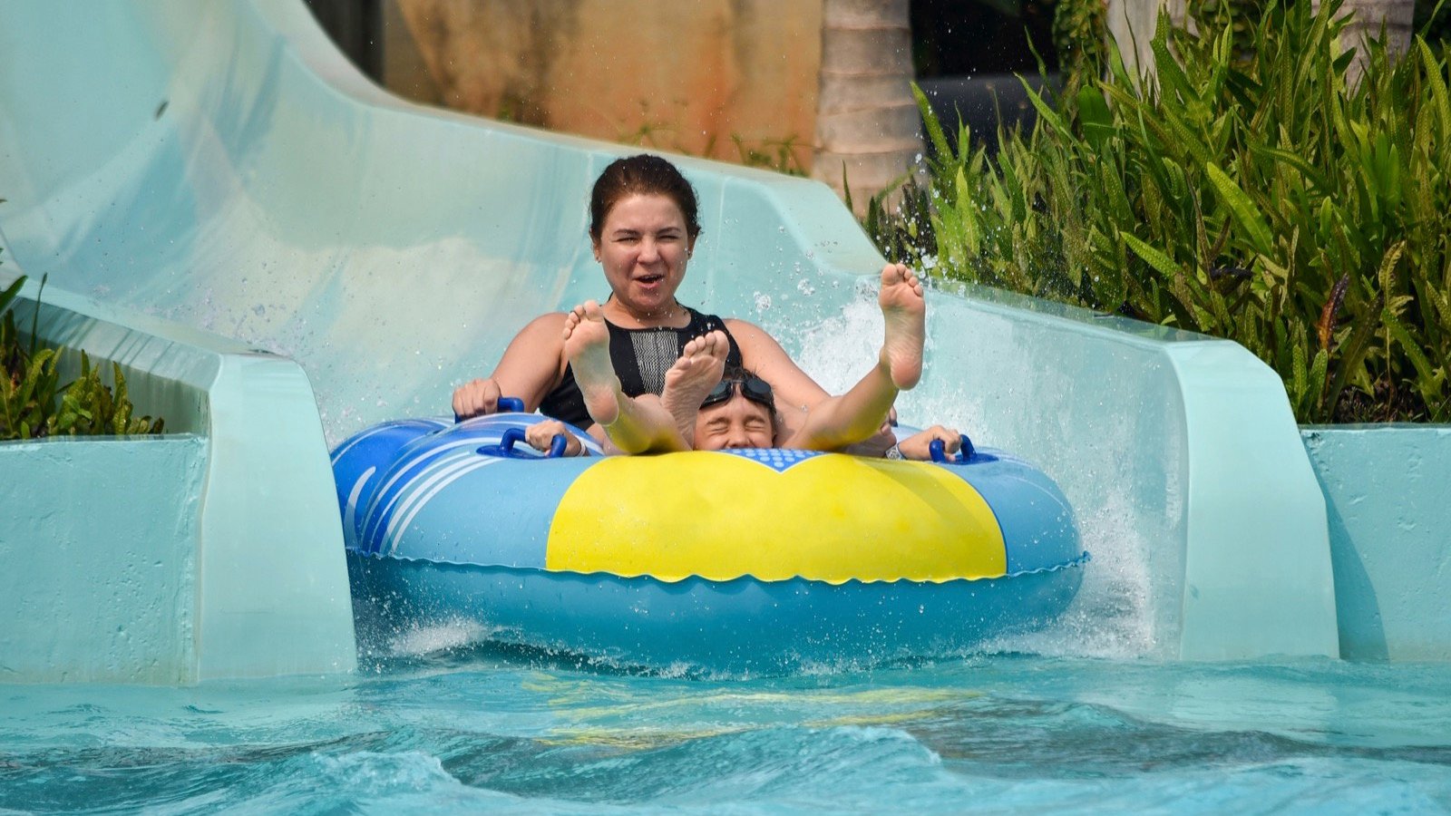 Happy young boy and his mom riding in waterpark