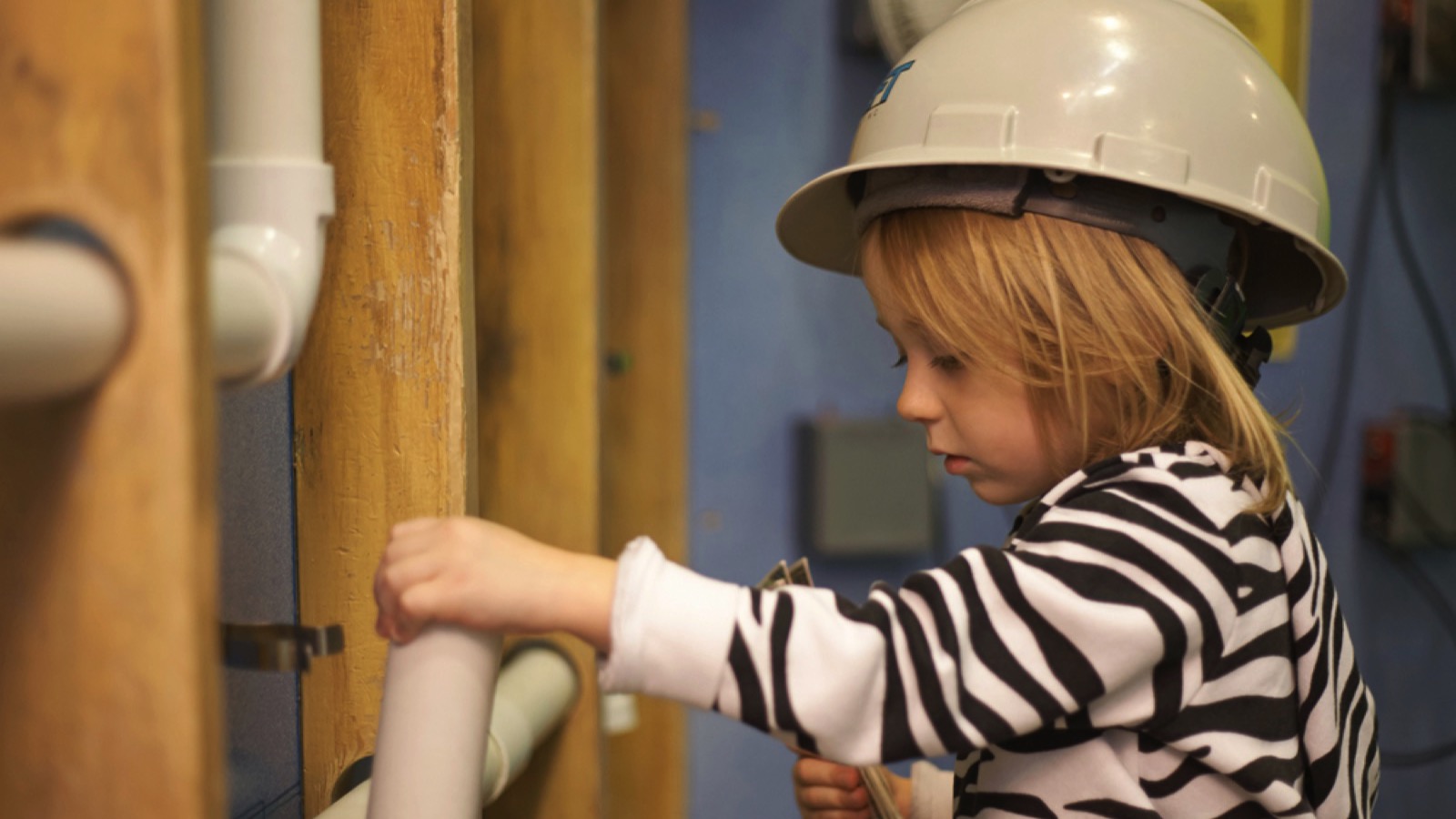 Little girl in helmet touching pipe