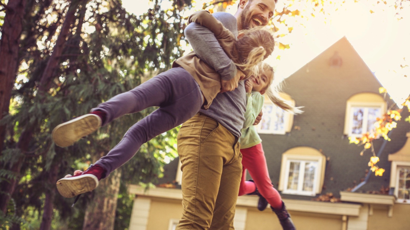 Man playing with daughters in yard