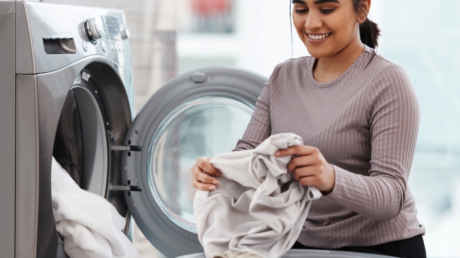 Woman taking laundry from machine