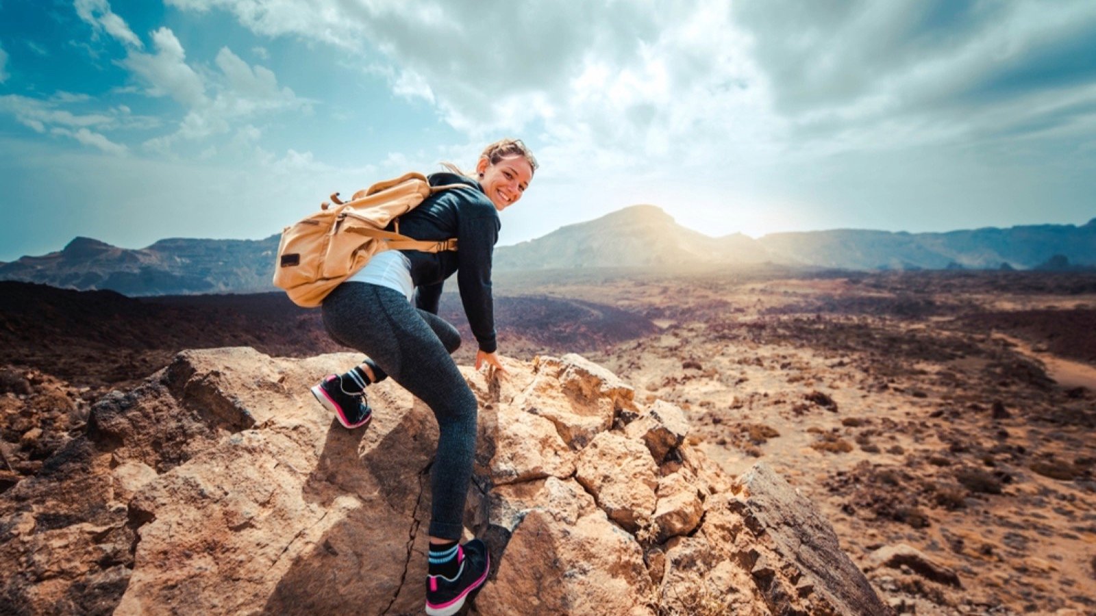 Happy woman hiker climbing rocks in national park