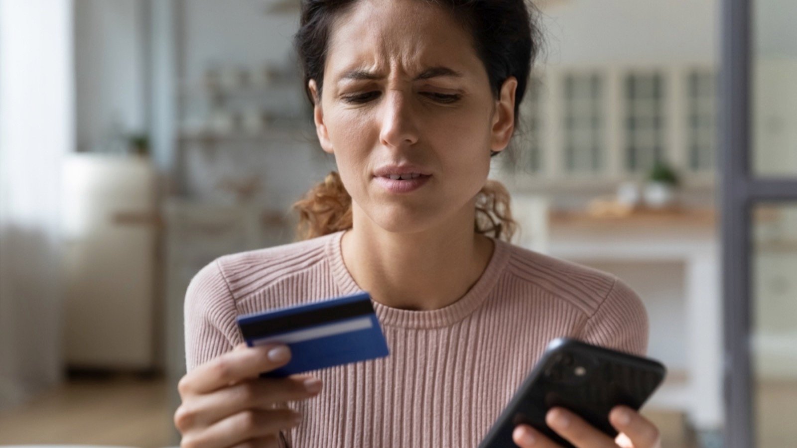 Irritated woman with mobile and credit card