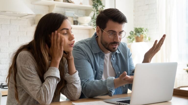 Frustrated couple looking on laptop
