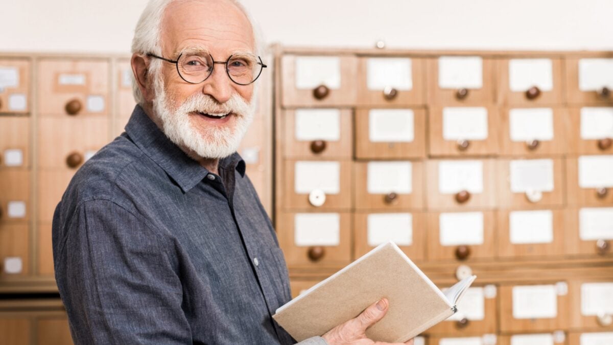 Smiling senior male Archivist holding a book