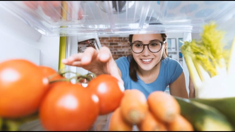 Woman taking tomatoes from fridge