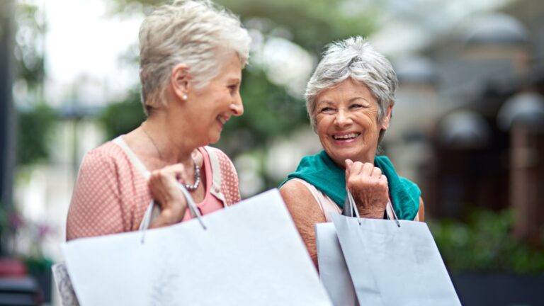 Two happy senior ladies with shopping bags