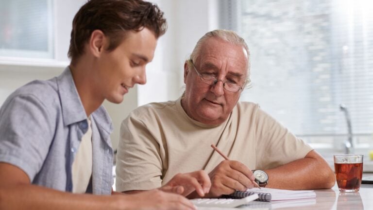 Elderly man helping grandson to manage personal finances