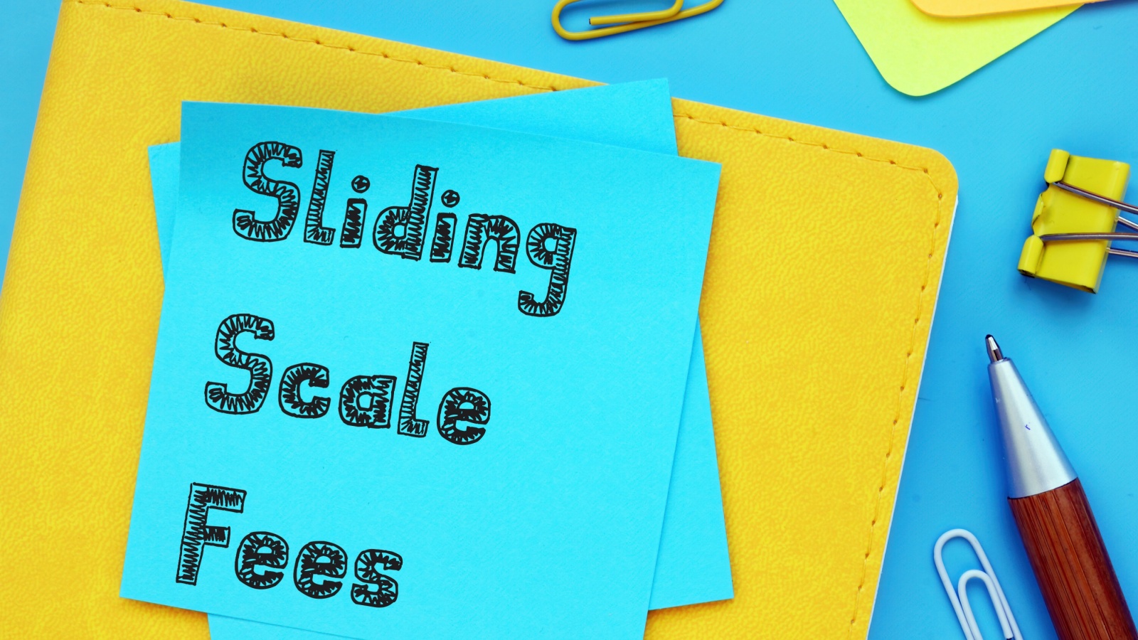 Sliding Scale Fees drawn on a blue post it note