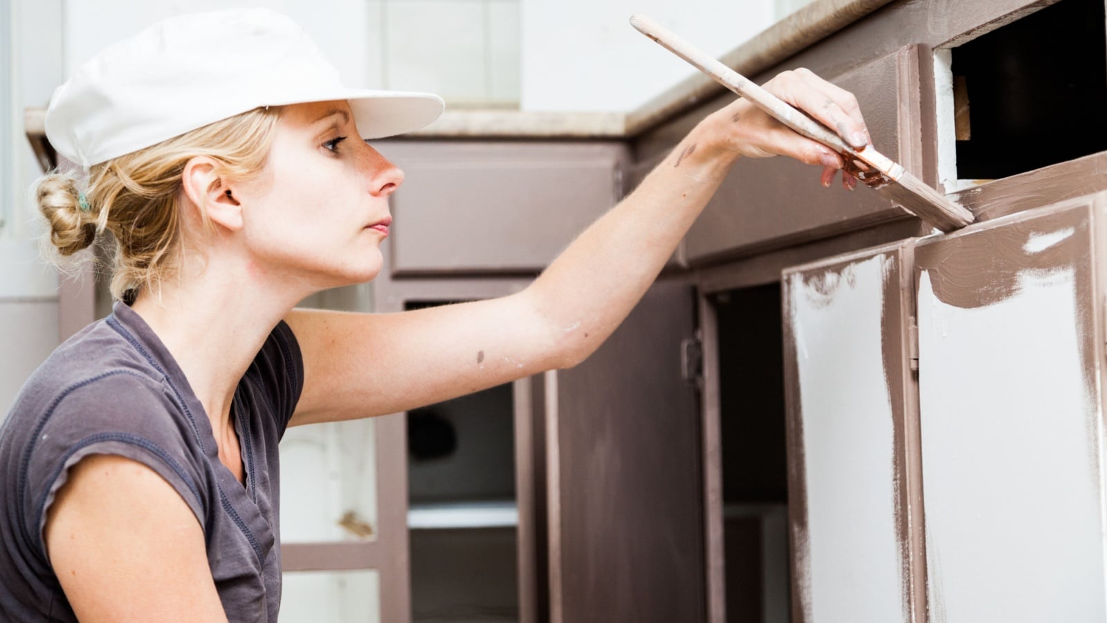 Woman painting her kitchen cabinets