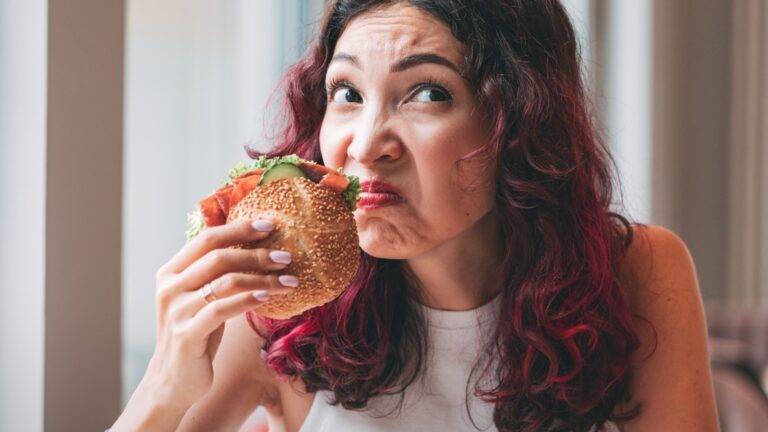 Woman sniffing her sandwich, not impressed with the quality or smell.