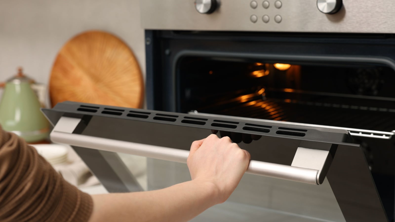 Woman using electric convection oven in kitchen, closeup
