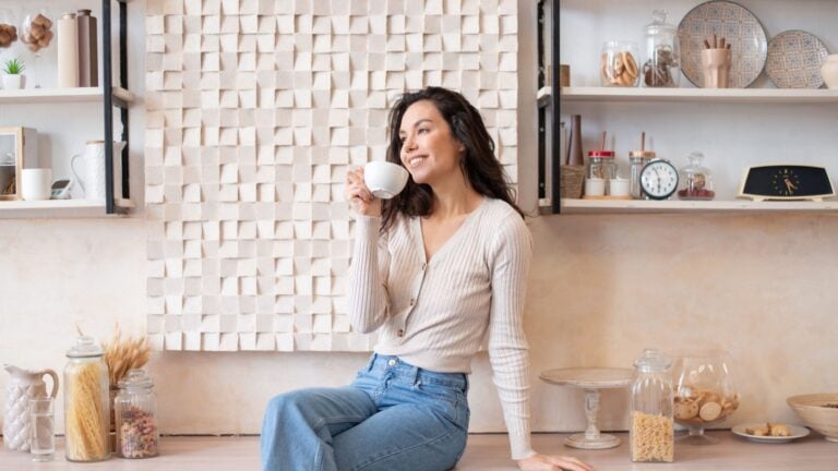 Carefree woman relaxing in cozy kitchen, drinking coffee.