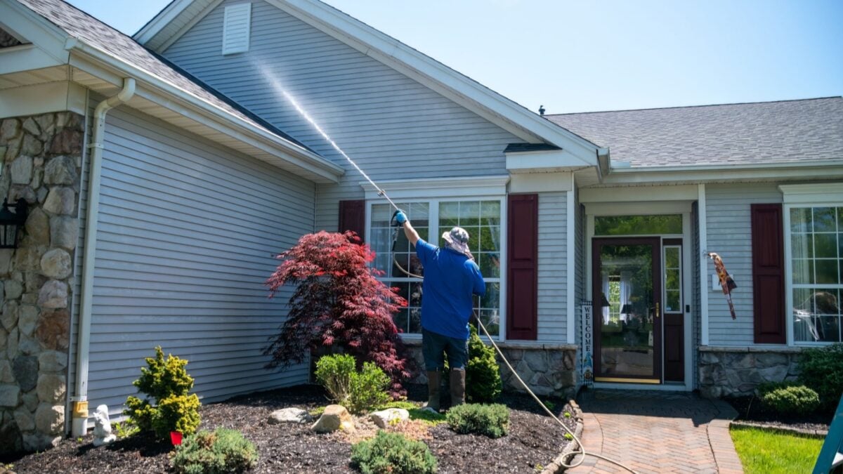 A man power washing the siding of a house.