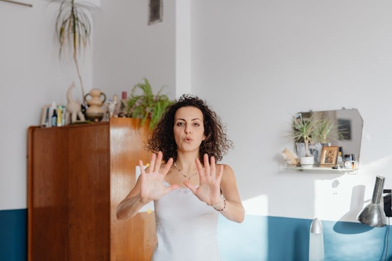 A woman with curly hair practices mindfulness exercises indoors, surrounded by plants.