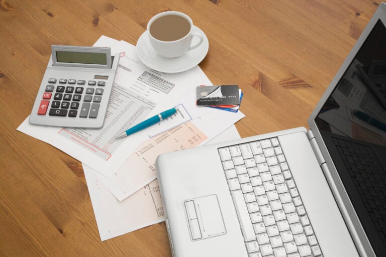 credit card companies on a laptop with credit card statements a cup of hot coffee and calculator in the background