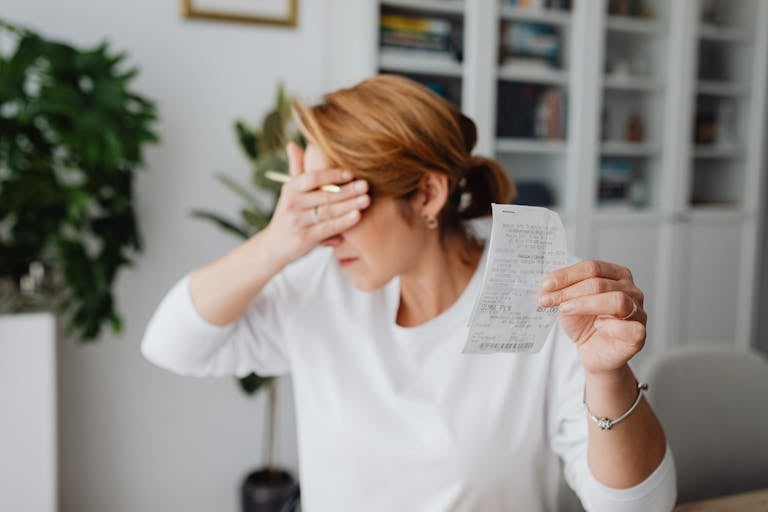 Cost of Living Woman experiencing stress while reviewing household expenses at home.