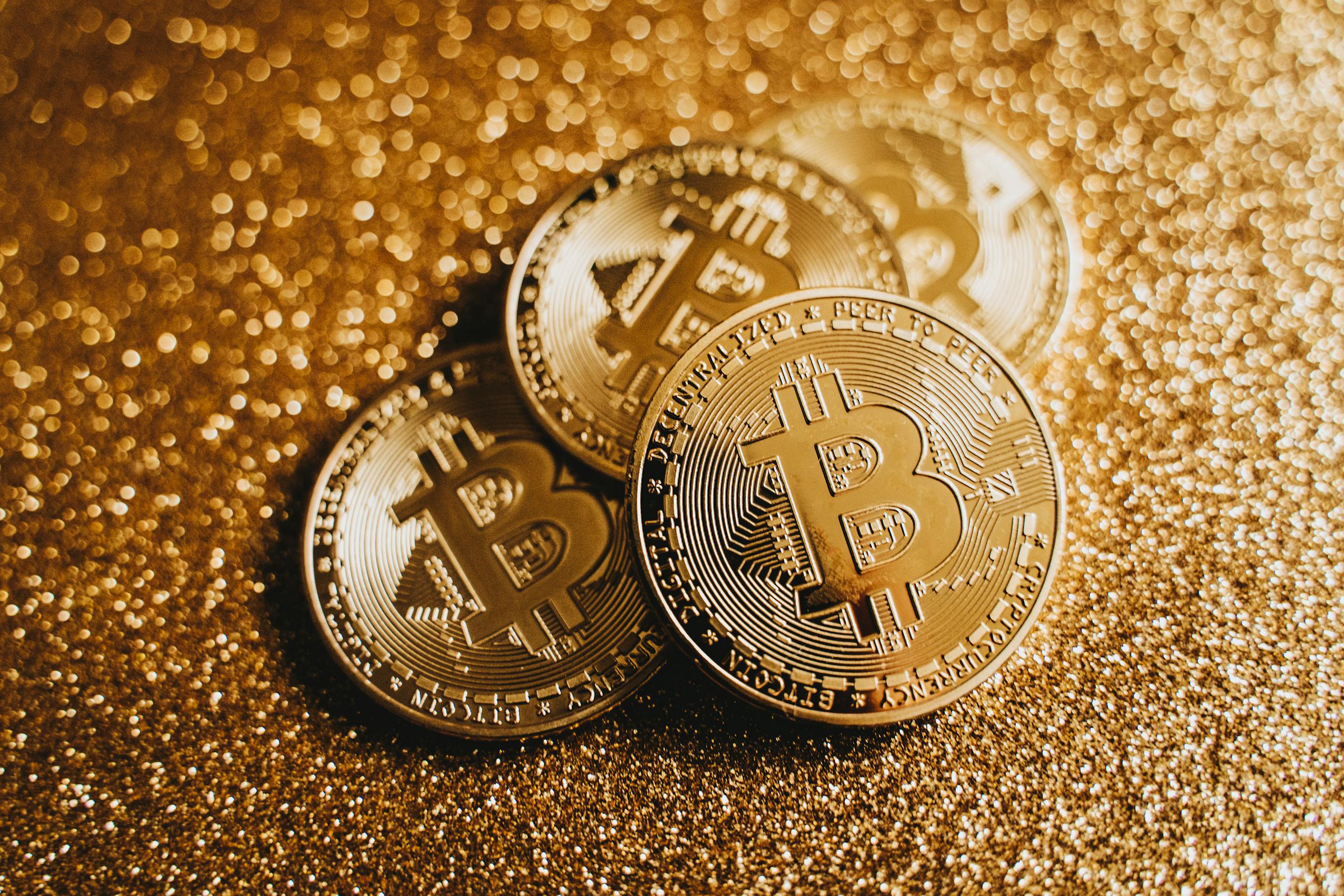 Crypto Close-up of golden Bitcoin coins on a sparkling, glitter-covered surface highlighting cryptocurrency wealth.