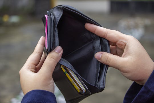 Frugal Habits An outdoor image of hands holding an empty black wallet, suggesting financial scarcity.