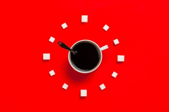 Buy Time Artistic coffee composition with sugar cubes on a striking red background, from above.