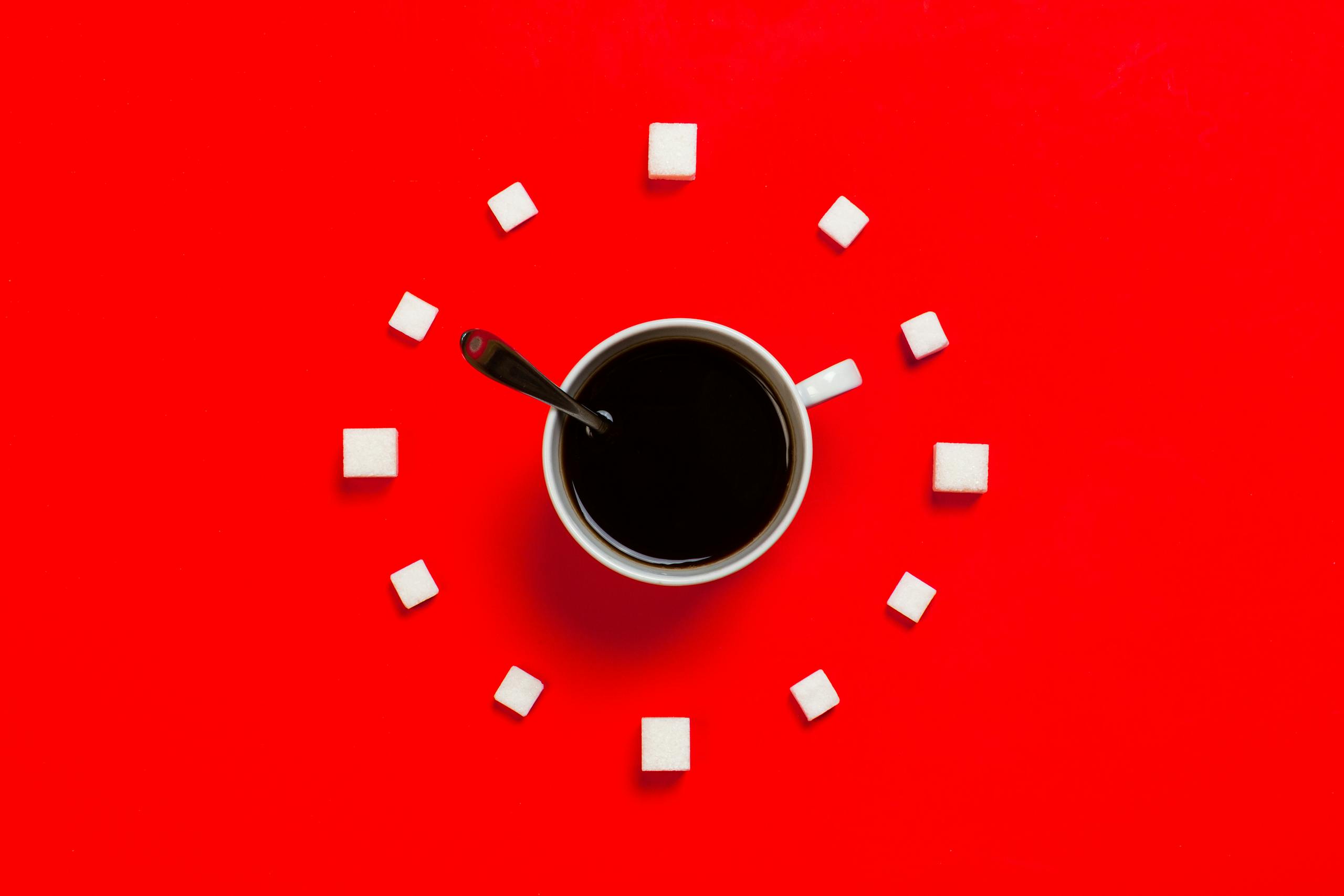 Buy Time Artistic coffee composition with sugar cubes on a striking red background, from above.