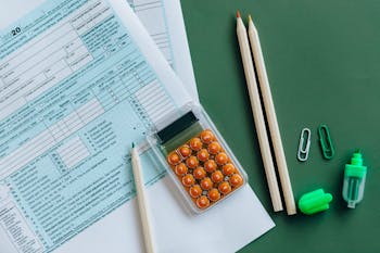 2026 Tax RefundFlat lay of tax forms, calculator, pencils, and clips on green surface, ideal for finance or accounting themes.