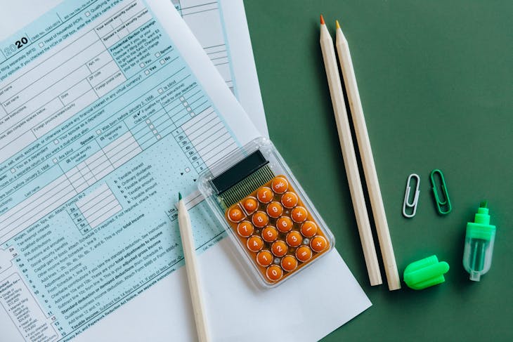 2026 Tax RefundFlat lay of tax forms, calculator, pencils, and clips on green surface, ideal for finance or accounting themes.