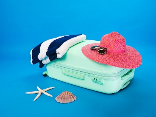 Summer Travel Beach essentials including a suitcase, hat, towel, and seashells on a bright background.