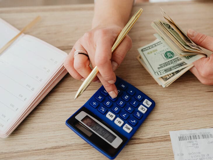 Woman entering numbers on a calculator to set up her 30 30 30 10 budget.