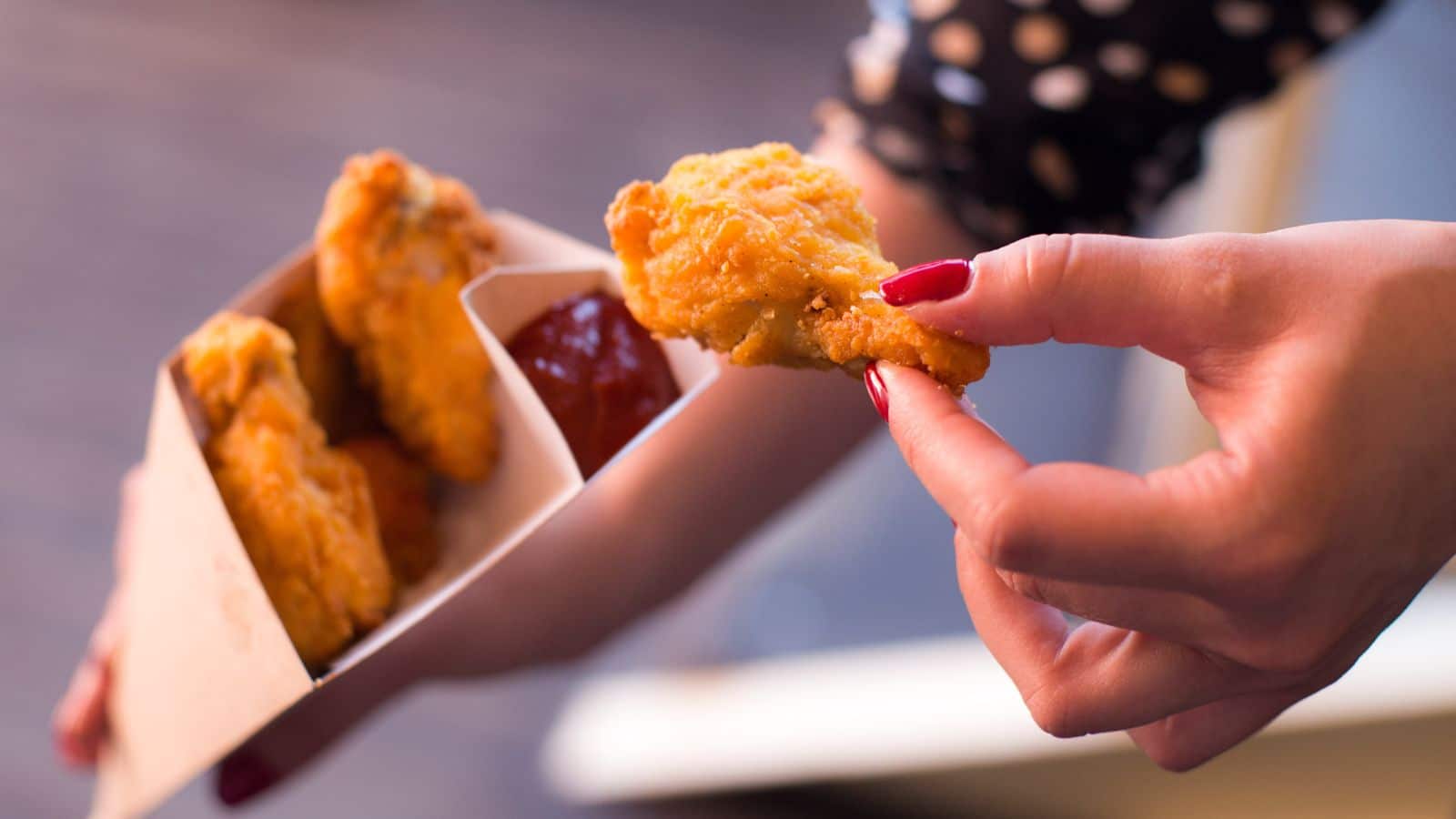A person is holding a bag of chicken nuggets, enjoying a delicious and affordable family day out while saving money.