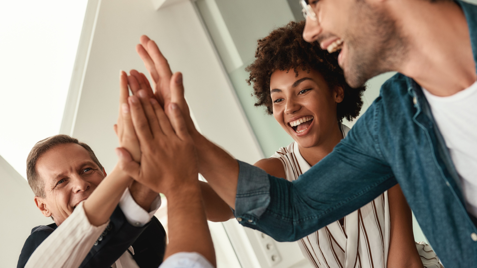 Celebrating success. Business people giving each other high-five and smiling while working together