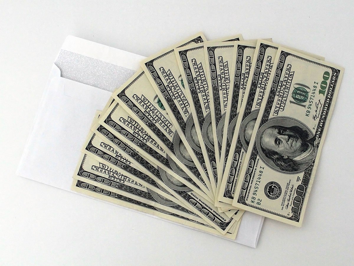 Setting up a budgeting envelopes system with cash and a white envelope.