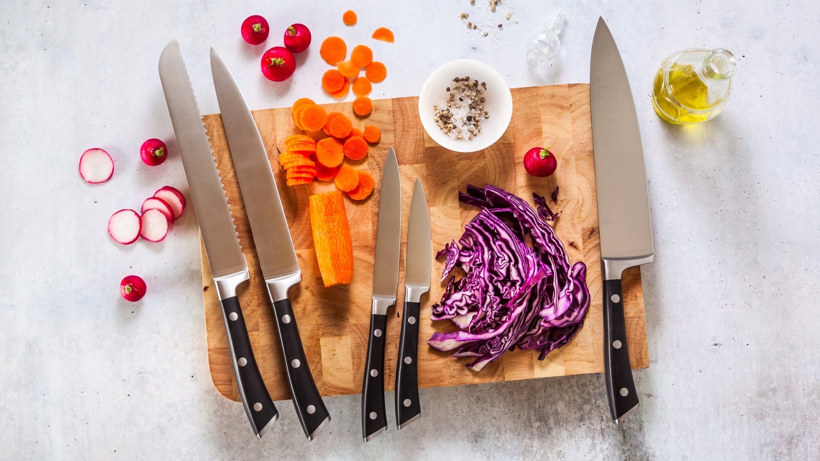 set of new professional kitchen knives on a wooden cutting board and vegetables