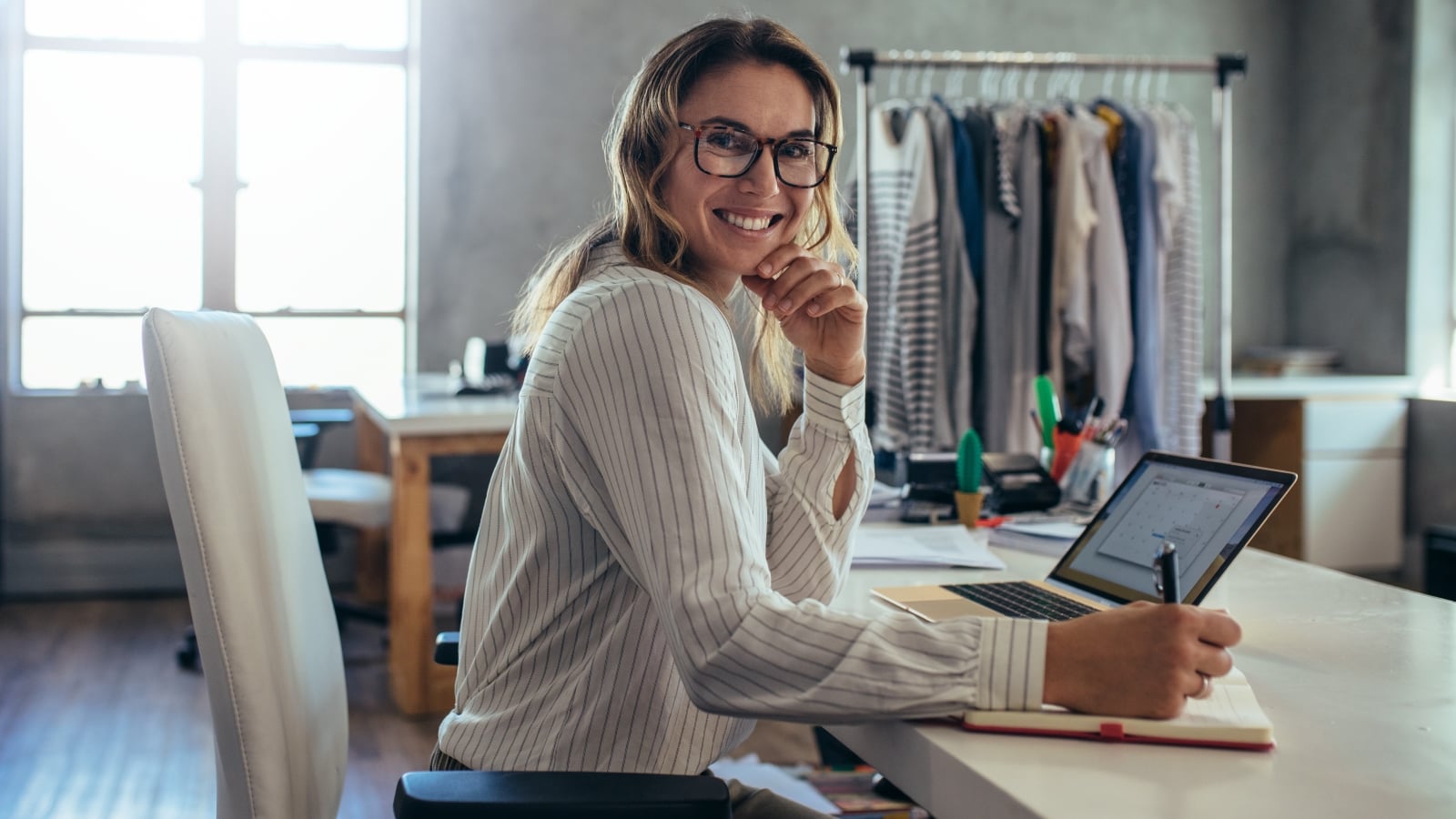 Smiling young woman taking note of orders from customers. Dropshipping business owner working in her office.