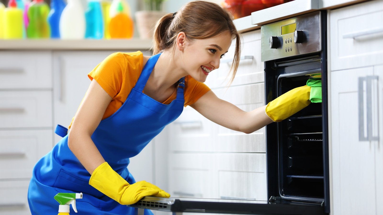 Woman washes an oven in the kitchen