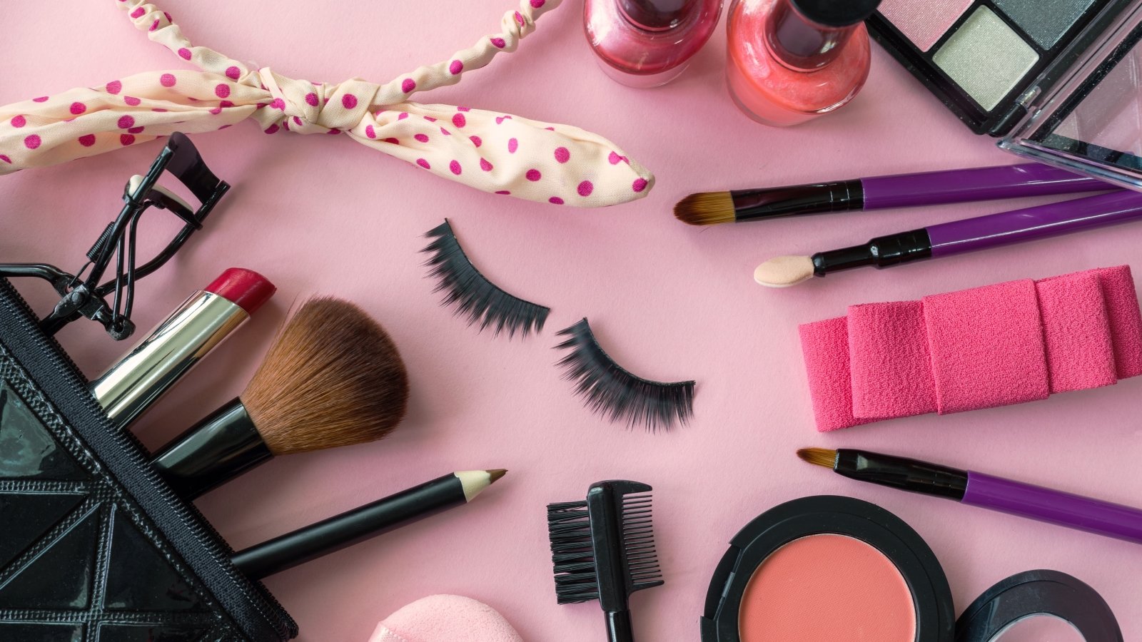 various makeup products and cosmetics isolated on pink background
