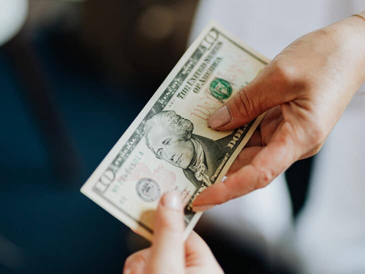Woman paying for a purchase in cash with a 10 dollar bill.